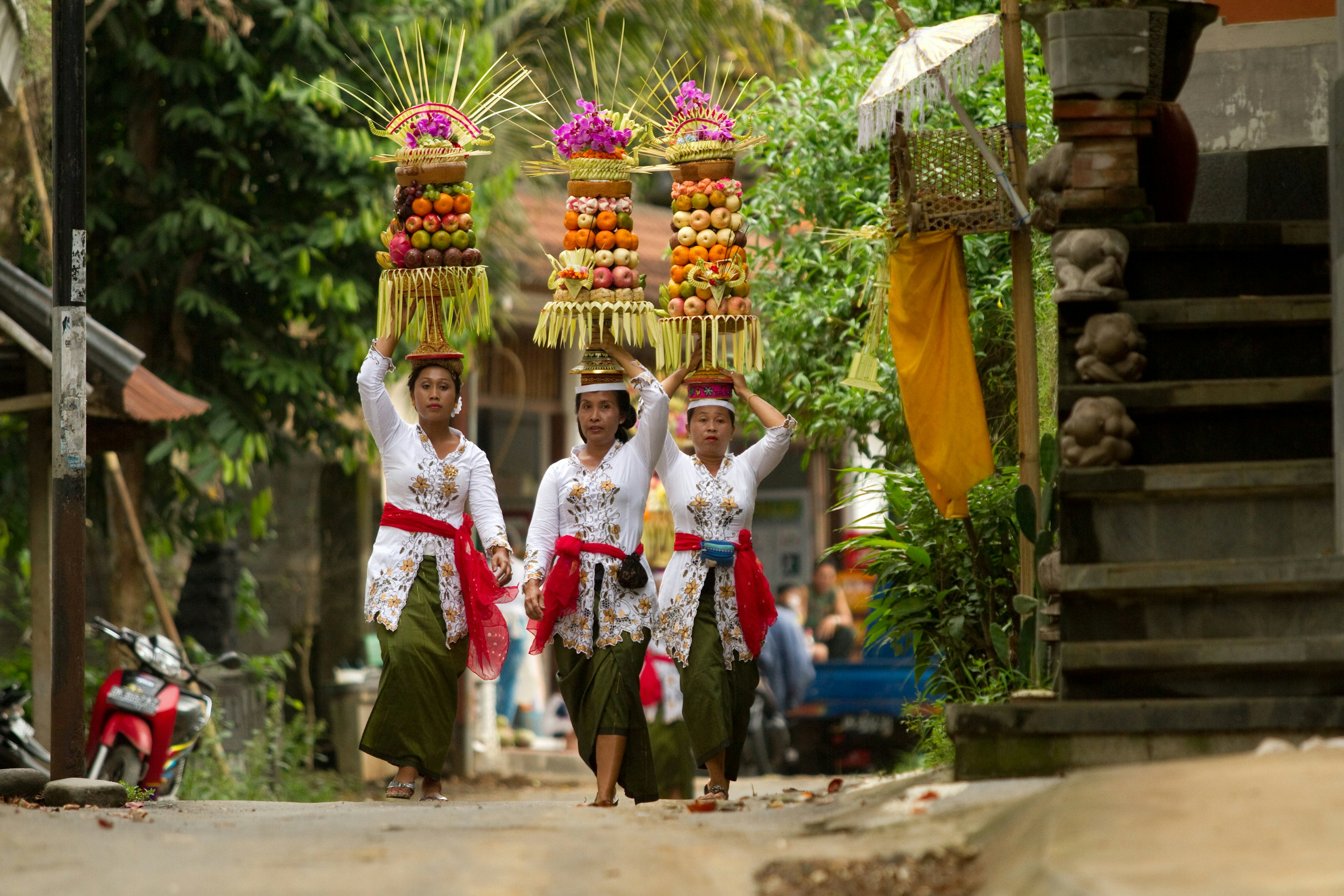 Village women carry offerings of food on their heads in a temple procession near Ubud