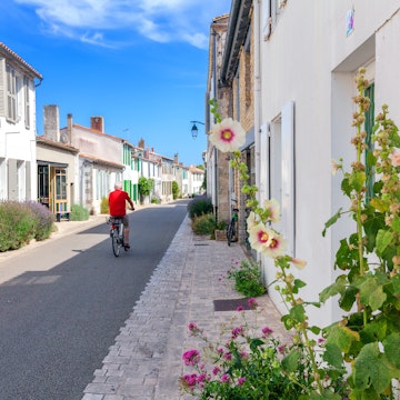 An elderly man rides a bike on a street in Ars en Re.