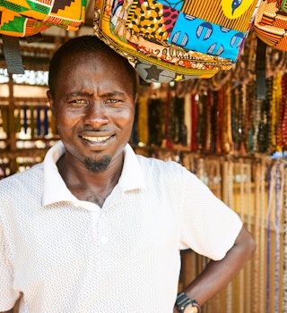 Koforidua, Eastern Region, Ghana - Feb 27, 2017: Portrait of handsome Ghanian man selling beads and necklaces in his shop in a beads market in west Africa.; Shutterstock ID 1052596556; your: Brian Healy; gl: 65050; netsuite: Lonely Planet Online Editorial; full: Ghana on a budget