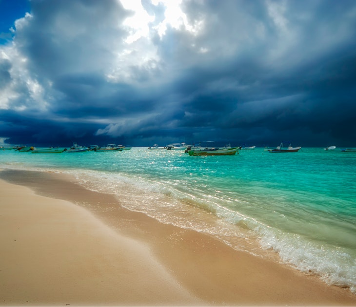 Storm and rain coming to the Caribbean sea of Playa del Carmen Mexico. Fishing boats anchored near the beach; Shutterstock ID 1589015776; your: Brian Healy; gl: 65050; netsuite: Lonely Planet Online Editorial; full: Best time to visit Playa del Carmen