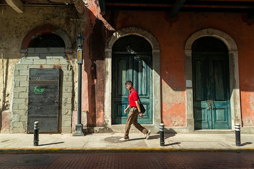 Un joven camina más allá de las puertas de una fachada histórica en el Casco Viejo, Ciudad de Panamá, Panamá