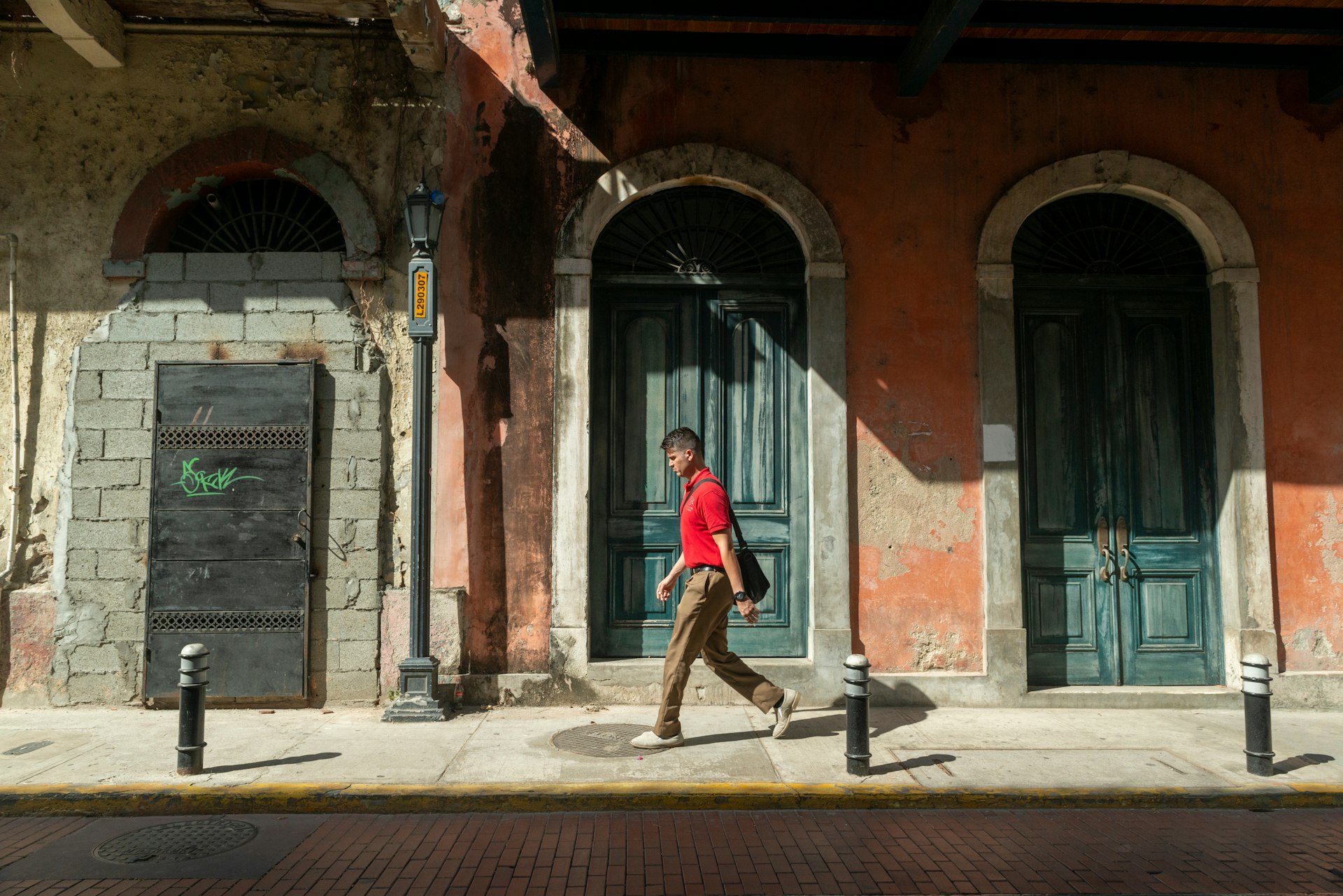A young man walks by the doorways in a historic facade in Casco Viejo, Panama City, Panama