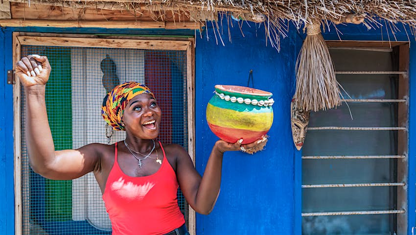 A smiling woman with a pot in her hand waits for rain in the dry season in Ghana