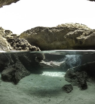 A woman is captured swimming underneath the water in a cave in Aruba. 