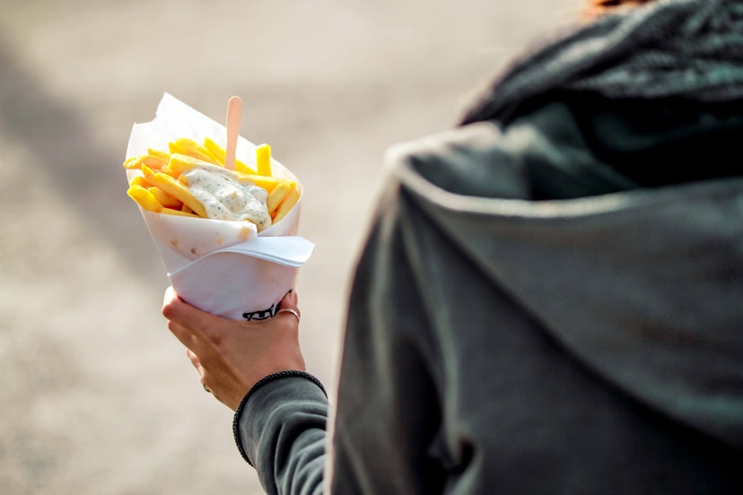 Brussels, Kingdom of Belgium. Tourist holds belgian fries in hand in the streets of Brussels. French Fries with mayonnaise.