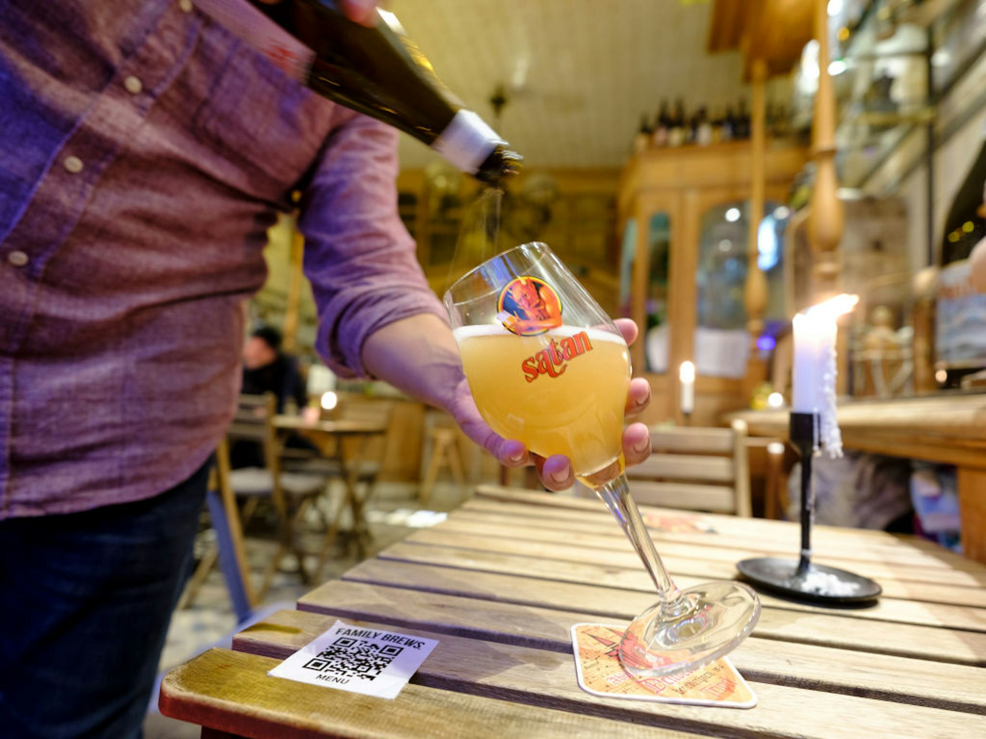 A red topped waiter serves a Satan white beer from the 'De Block' breewery in the pub 'Family Brews' in the Rue des Harengs in Brussels, Belgium.