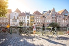 Woman traveling in Ghent old town, Belgium - stock photo
Sunrise view on the water channel with beautiful old buildings with woman standing near the bicycles in Ghent city