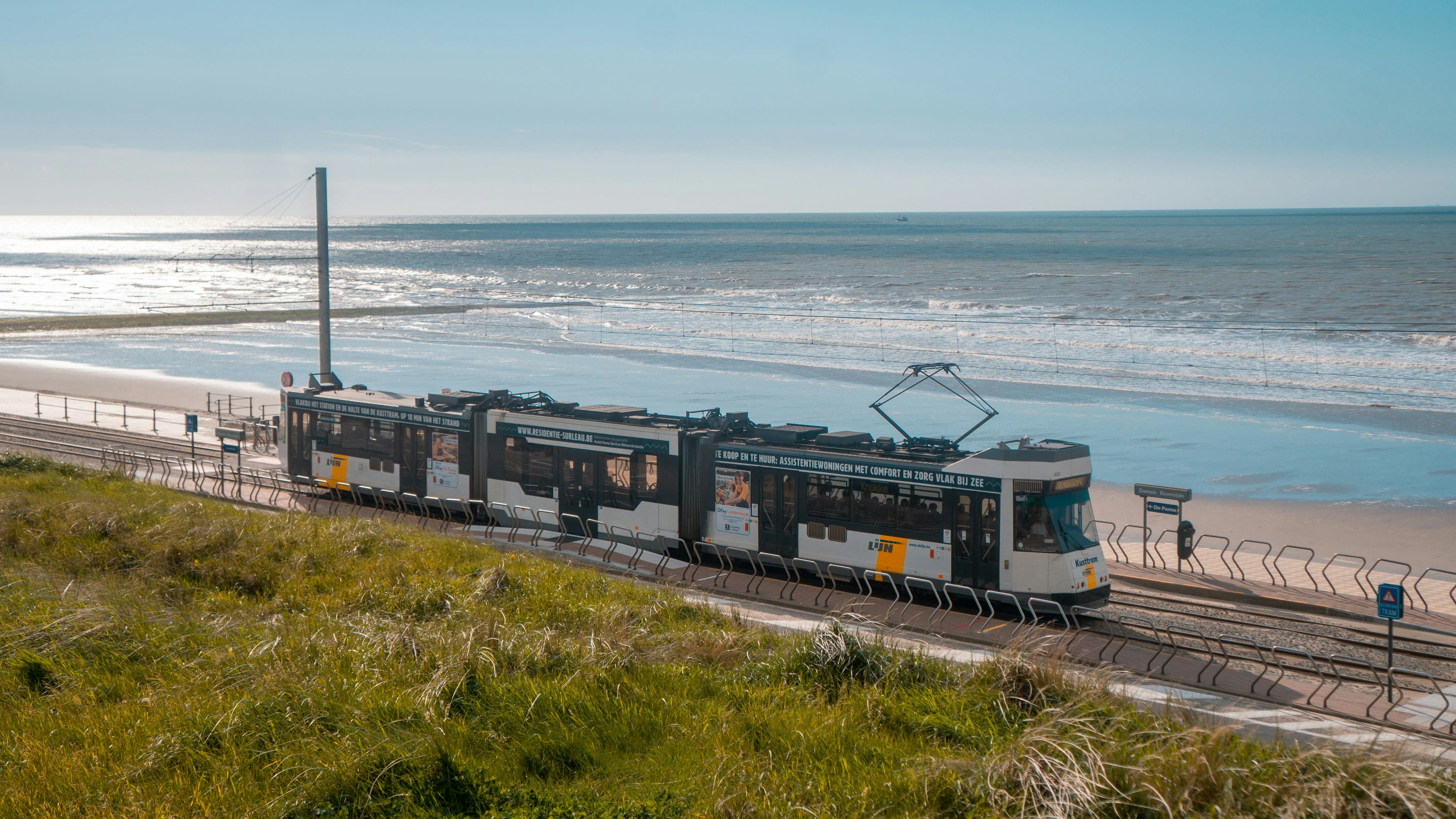 The coastal tram in Belgium passing alongside the beach in the sunshine