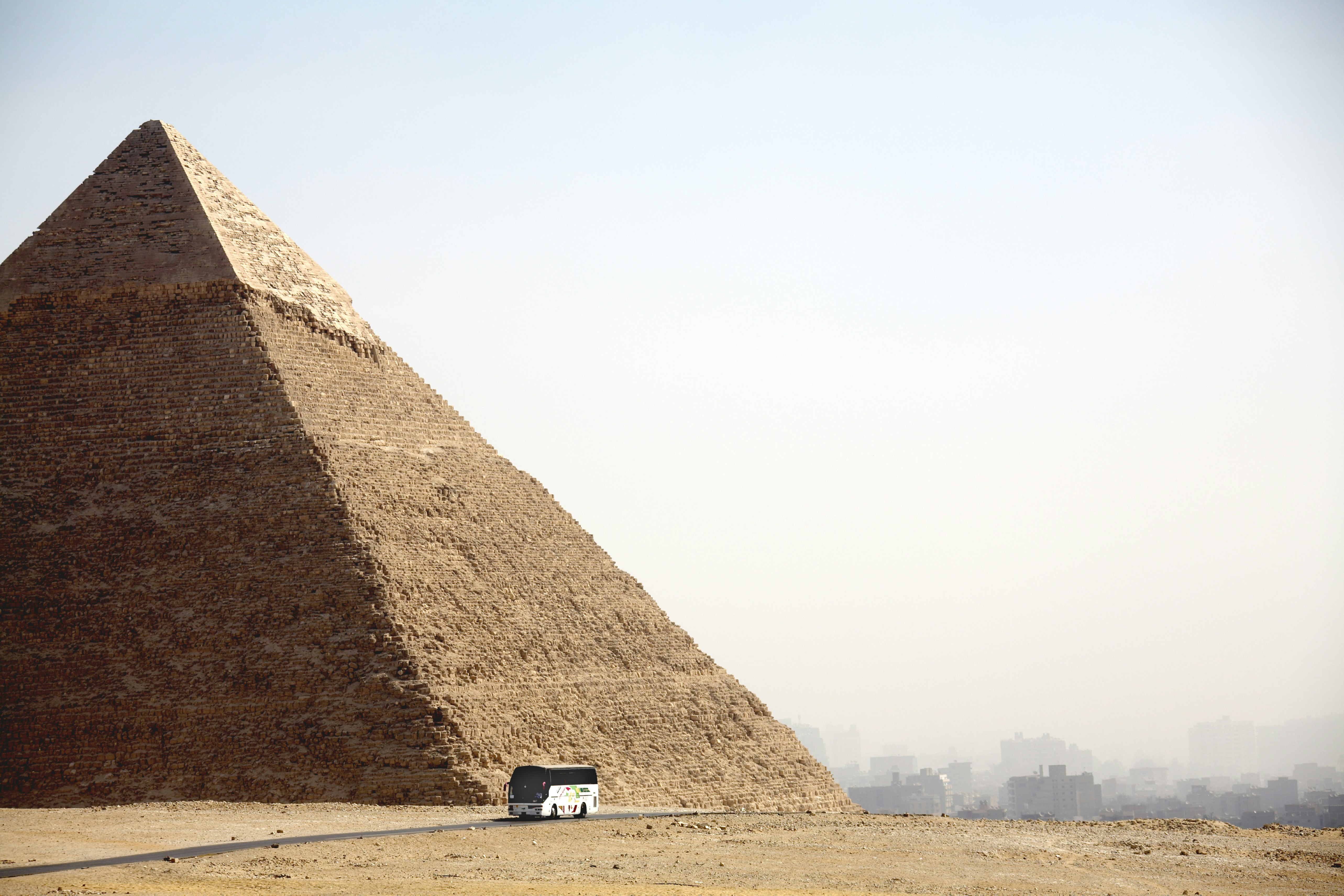 A coach bus drives past a large pyramid in Cairo, Egypt