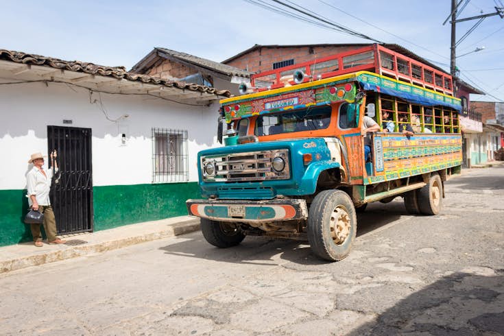A colorful chiva bus pulls into a street in Yolombó, Antioquia, Colombia