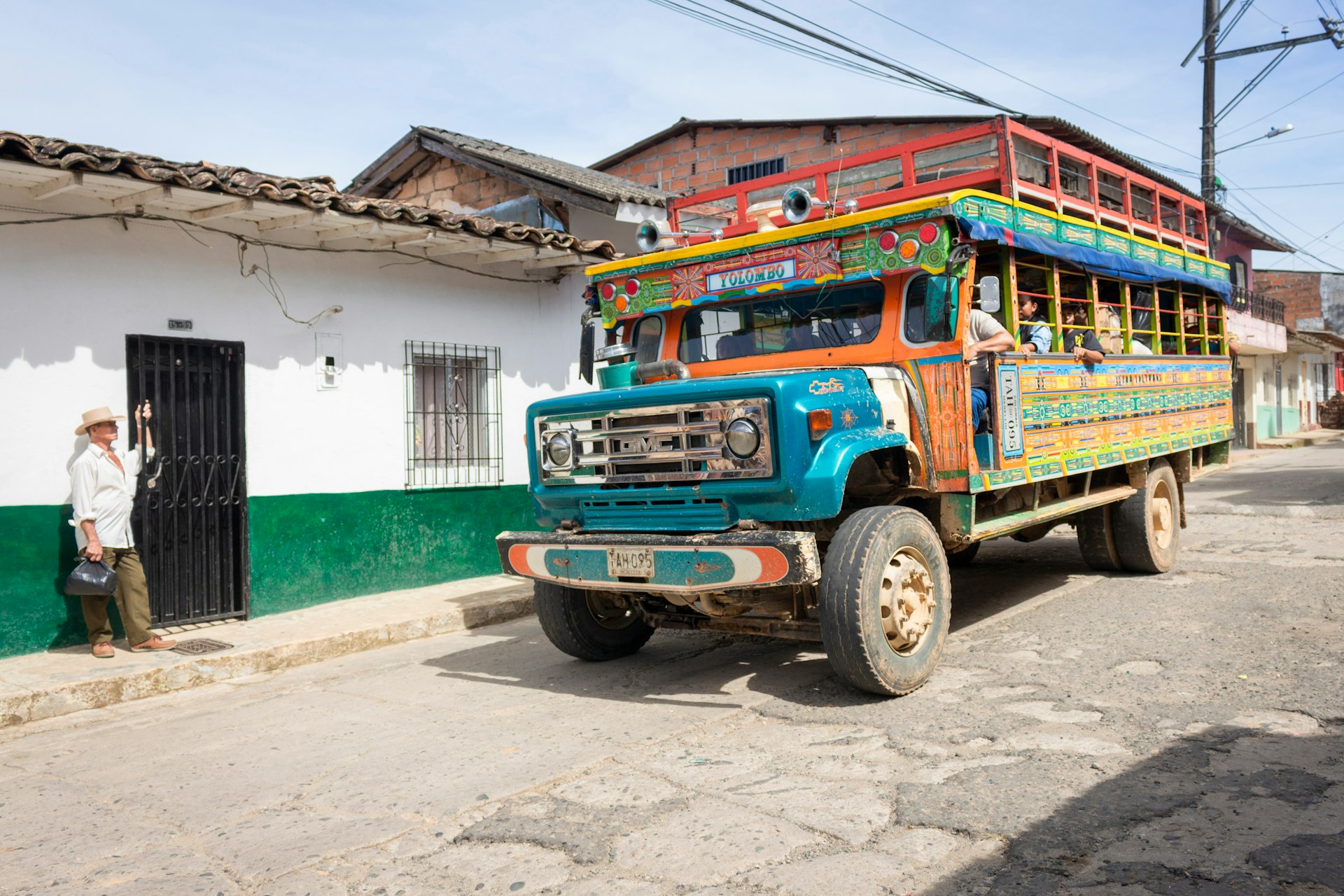 A colorful chiva bus pulls into a street in Yolombó, Antioquia, Colombia