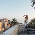 Caucasian woman standing on park wall photographing cityscape - stock photo