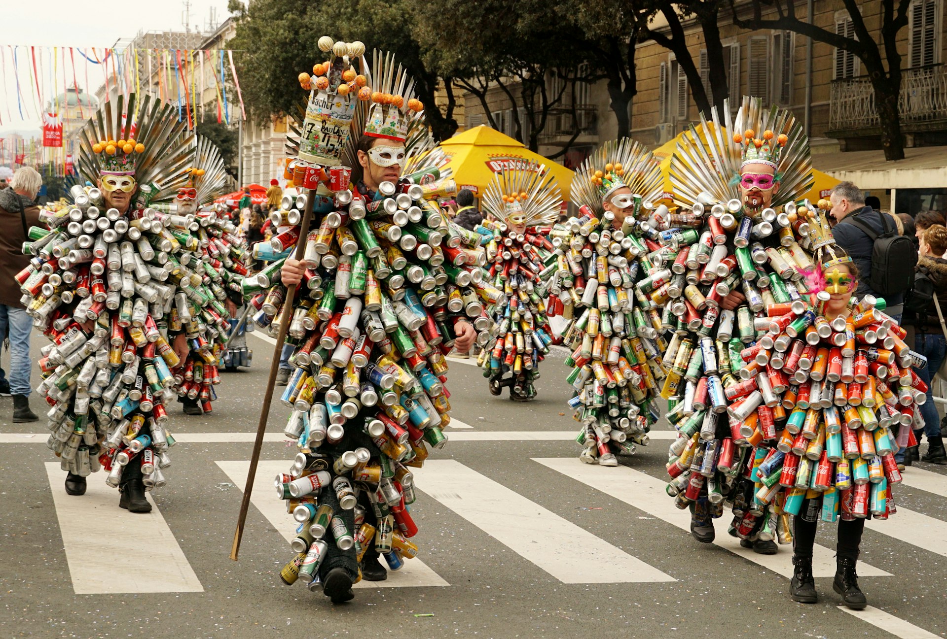 A group of people in a carnival parade dressed in costumes made of beverage cans