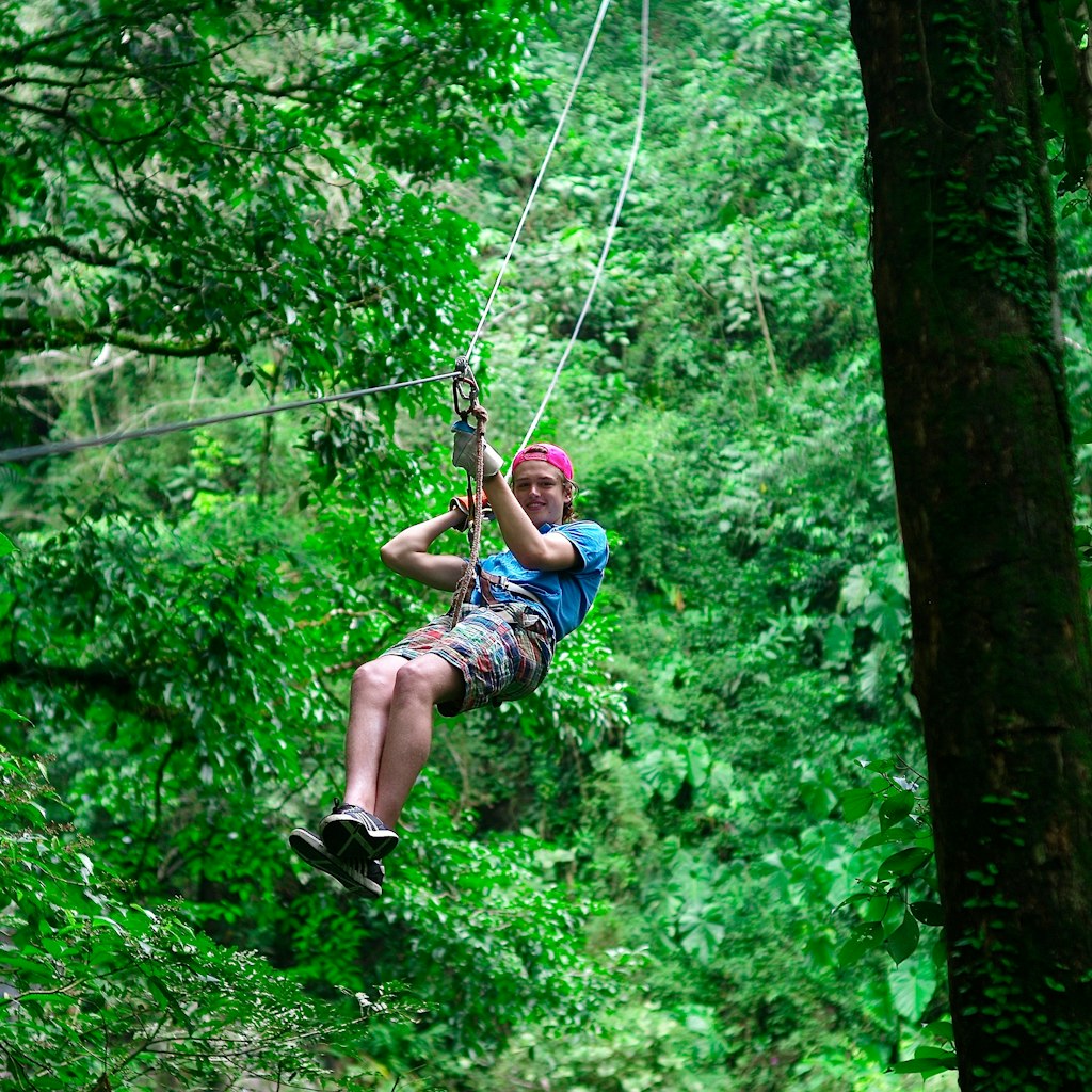 A man ziplines down a rope in over a jungle canopy in El Valle, Panama. 