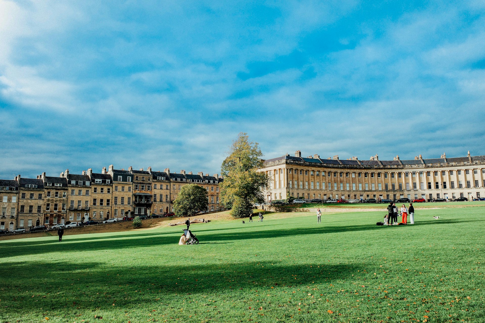 People enjoy a the sunny afternoon on the grass in front of the Royal Crescent, a curved line of honey-colored buildings in Bath, England. 