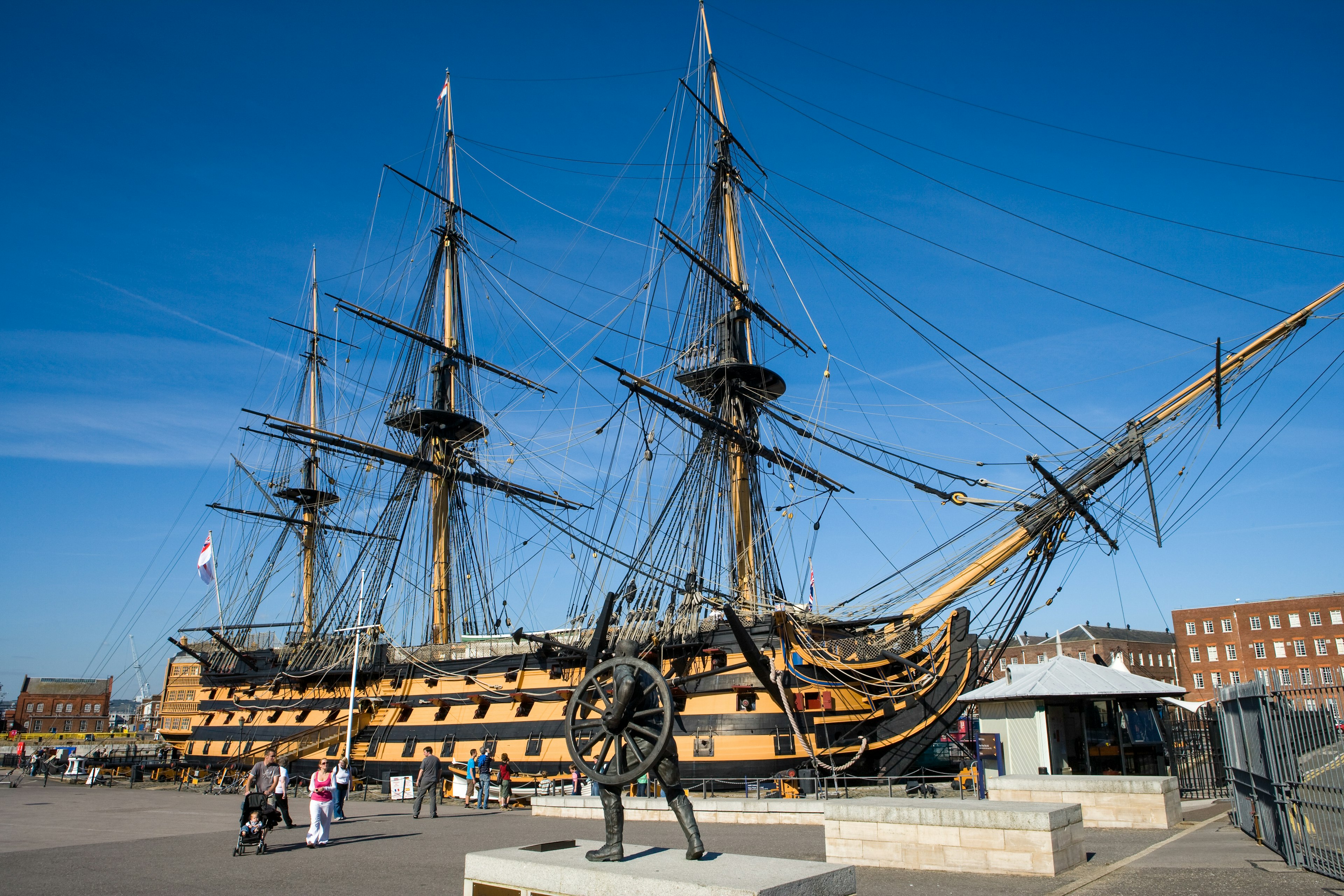 People walk in front of the three-mast HMS Victory ship in Portsmouth, Hampshire, England