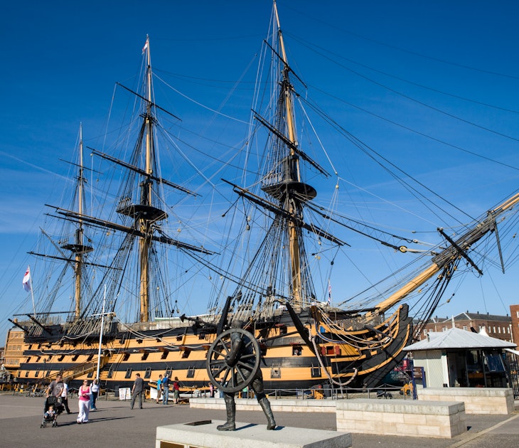 People walk in front of the three-mast HMS Victory ship in Portsmouth, Hampshire, England