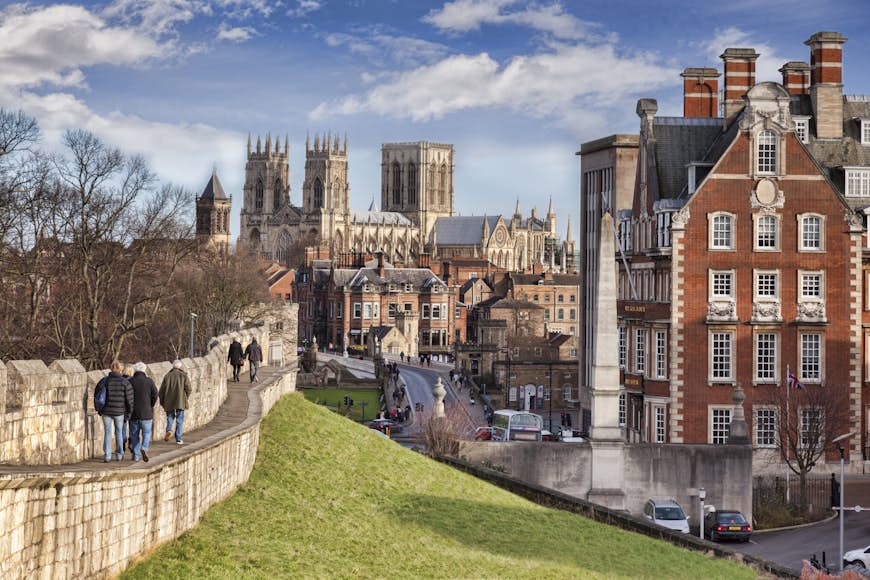 People walking the city walls in York, with a view towards the Gothic Minster