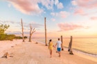 Couple walking on beach at sunset romantic travel getaway, idyllic Florida destination, Lovers Key State Park in the gulf of Mexico. Woman and man holding hands relaxing. Southwest Florida.
