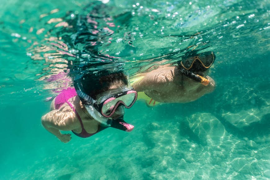 Couple snorkeling side by side in turquoise water 
