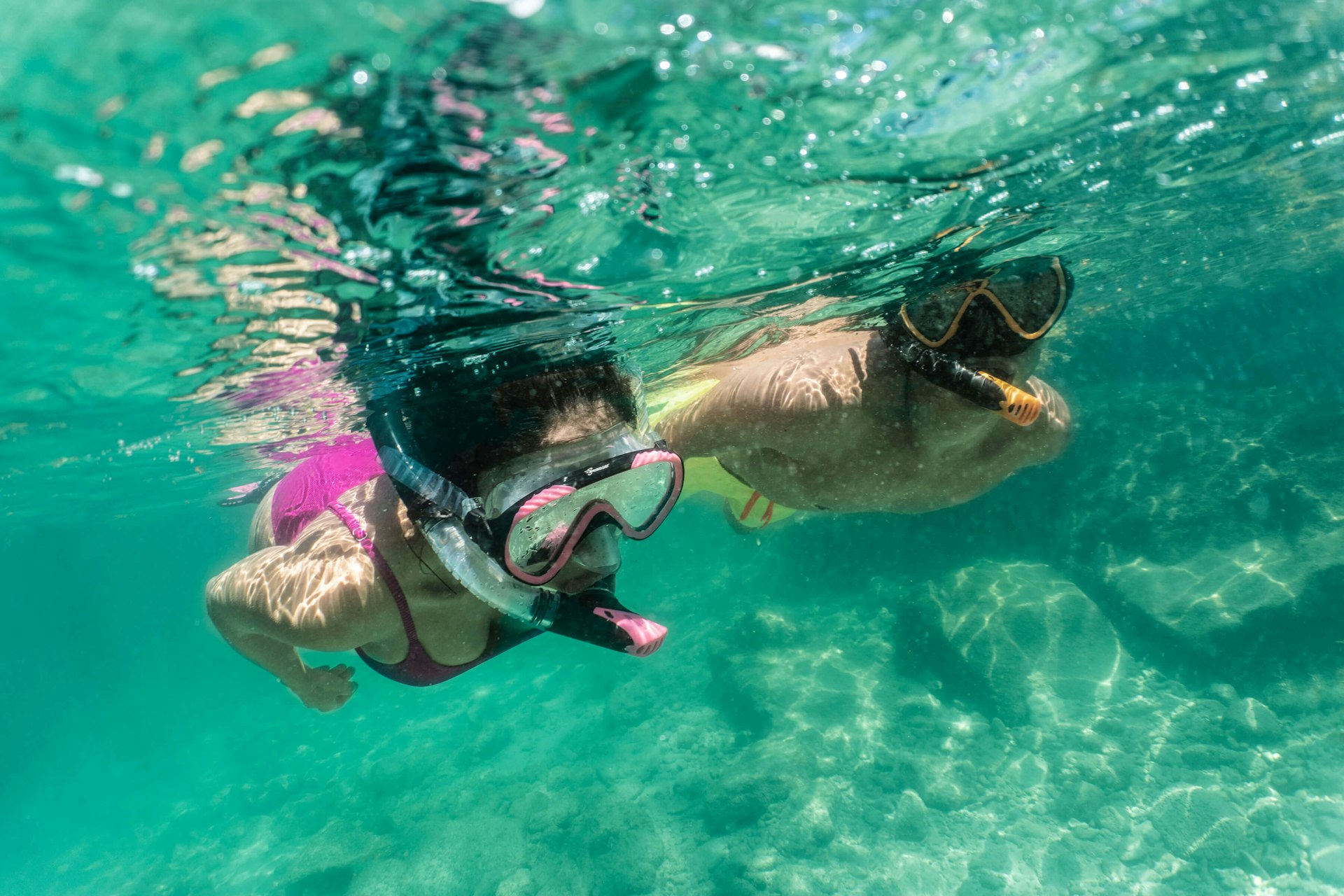 Couple snorkeling side by side in turquoise water 