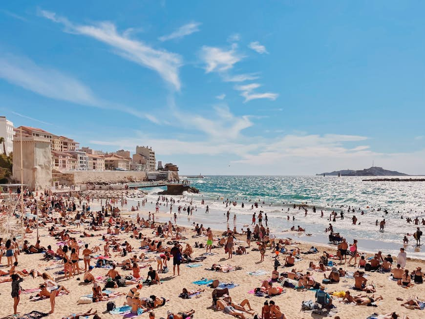 Hoardes of people relax on the sandy beach on a sunny day