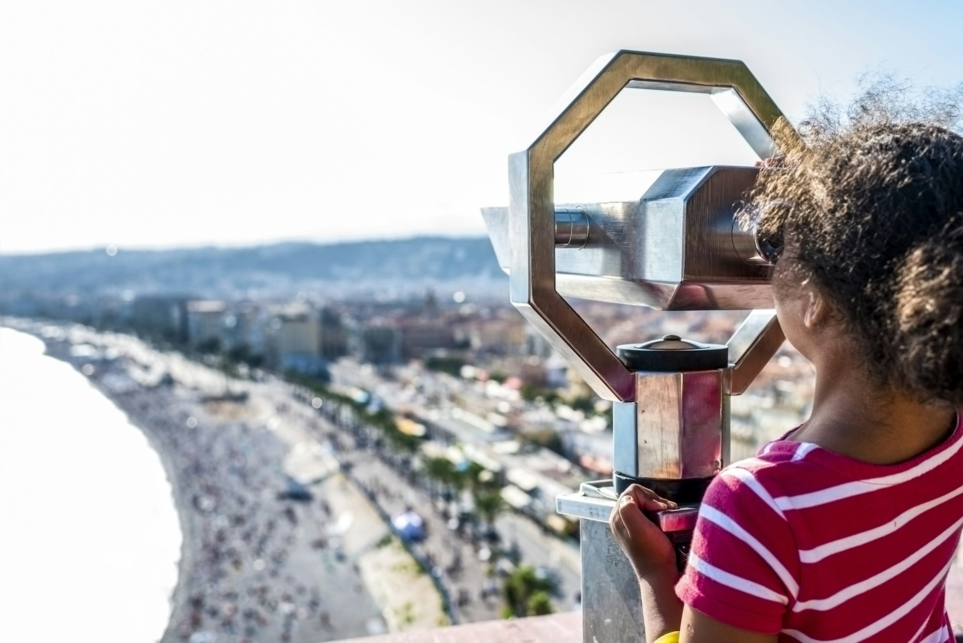 A child looks through binoculars down towards the beach in Nice, France