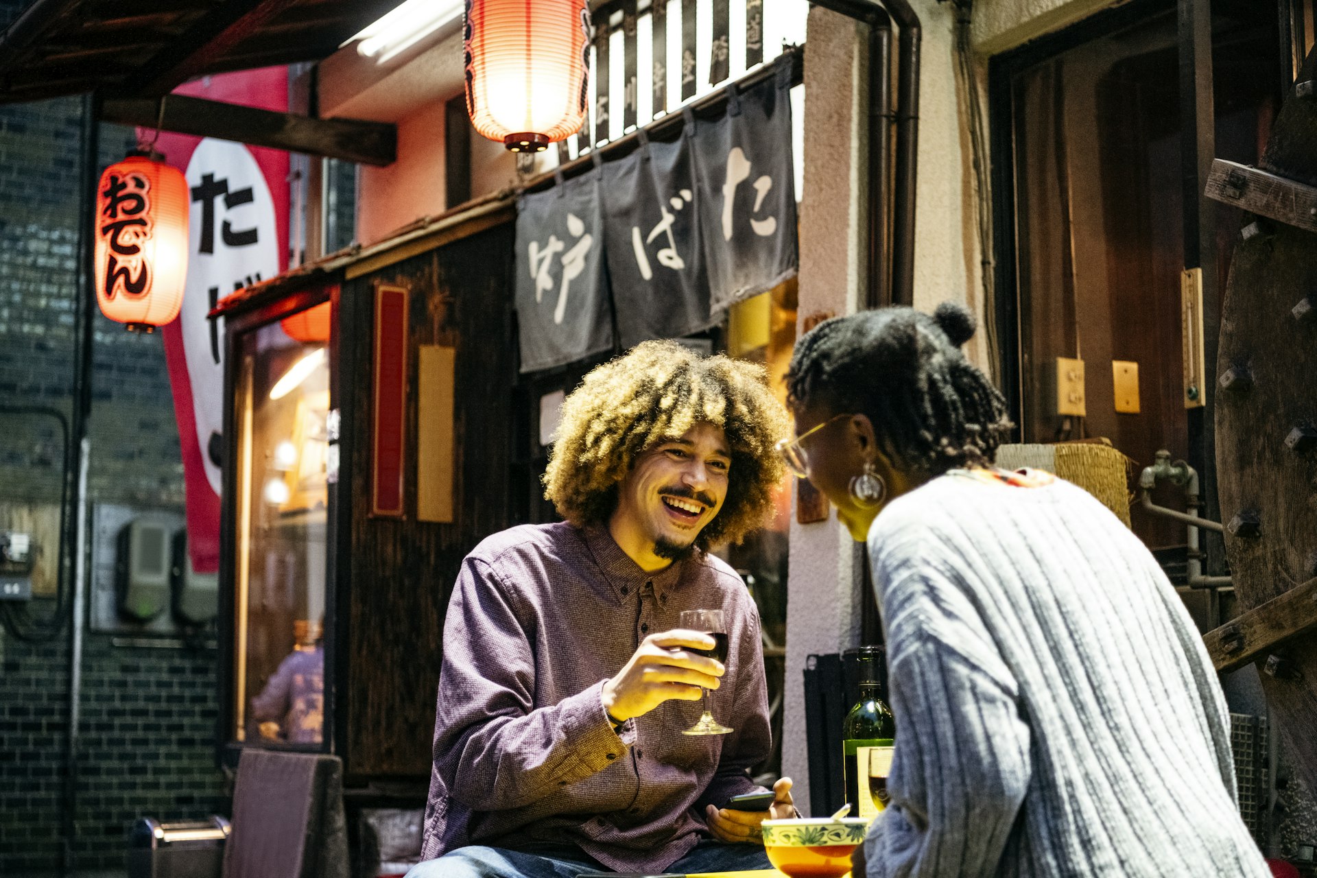 Attractive couple laughing with wine outside Japanese restaurant