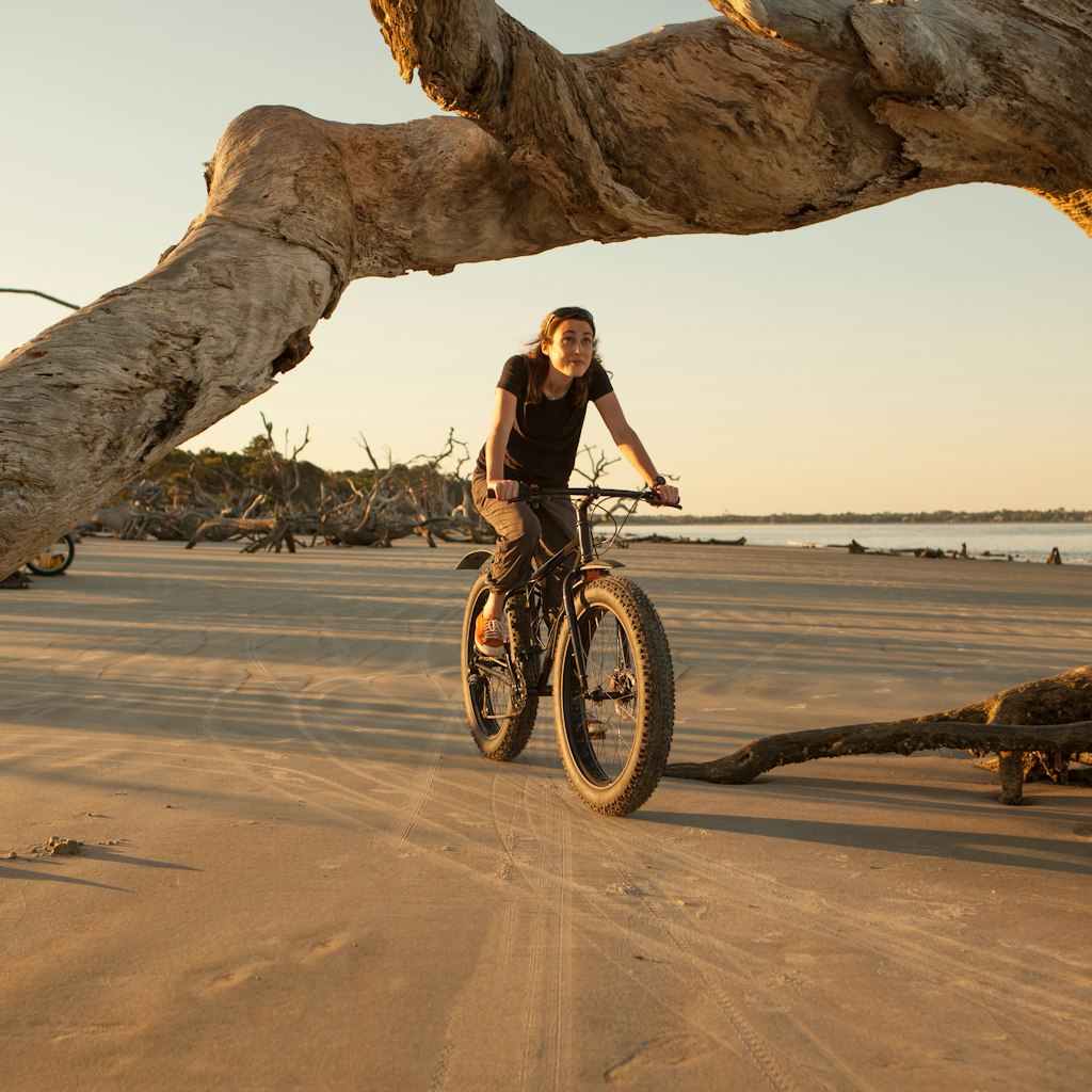 Woman riding her fatbike along a beach on the ocean.