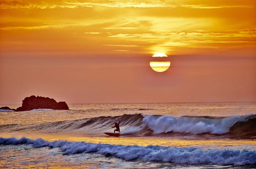 A surfer at sunset on the Atlantic Ocean near Sagres