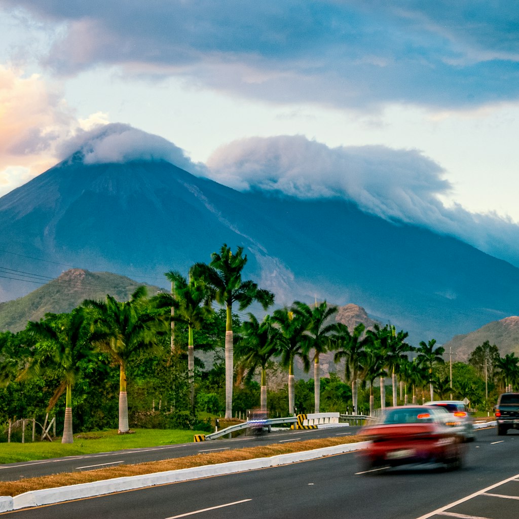 Cars drive past Volcanoes Fuego y Acatenango in Palin, Guatemala, at sunset