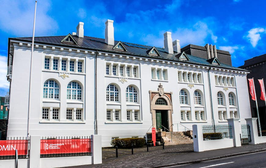 The House of Collections, a large white building with arched windows and one central door, sits on a street in Reykjavík