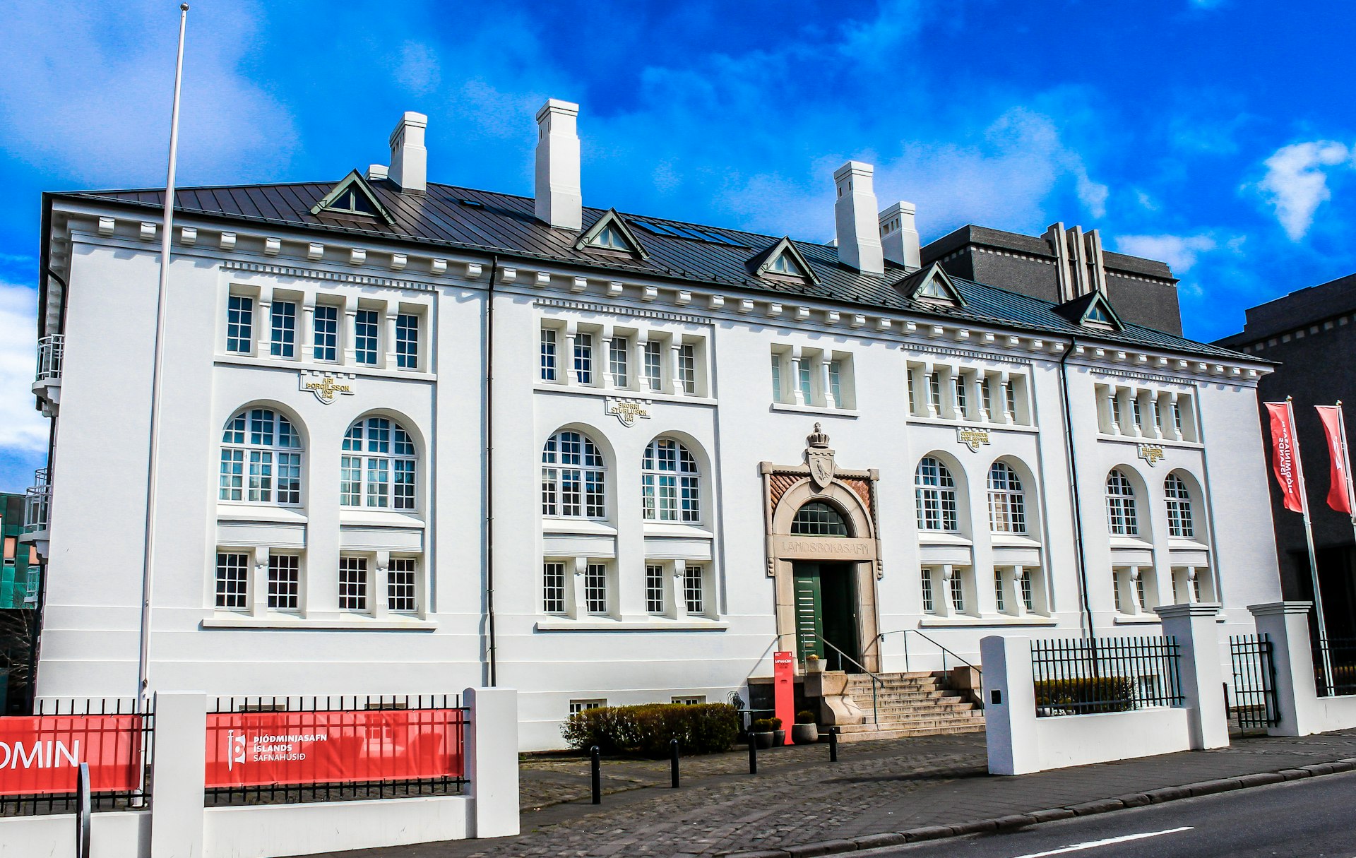 The House of Collections, a large white building with arched windows and one central door, sits on a street in Reykjavík