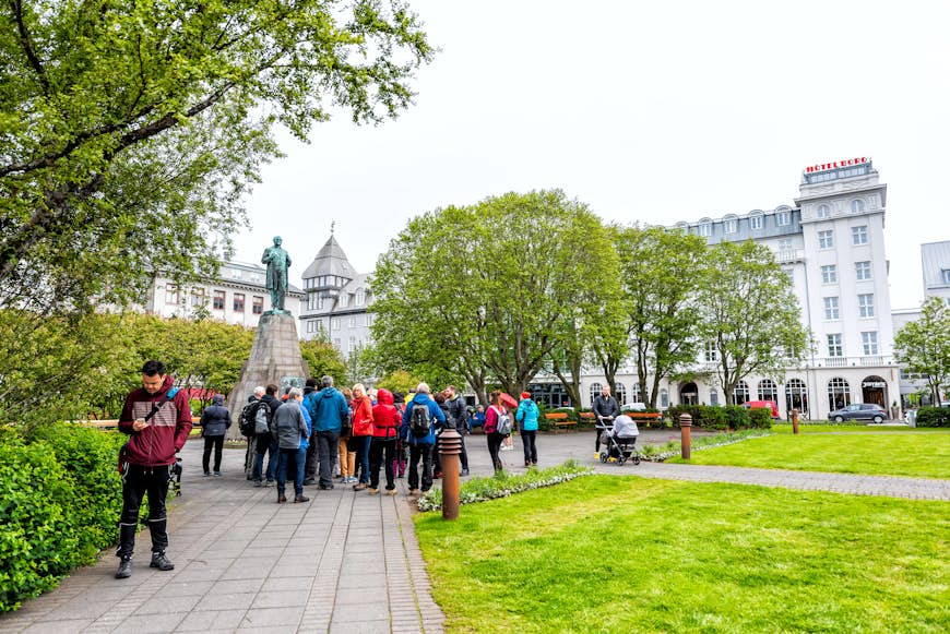 Downtown city street with Sigurdsson Statue in Austurvollur Park and tour group people
