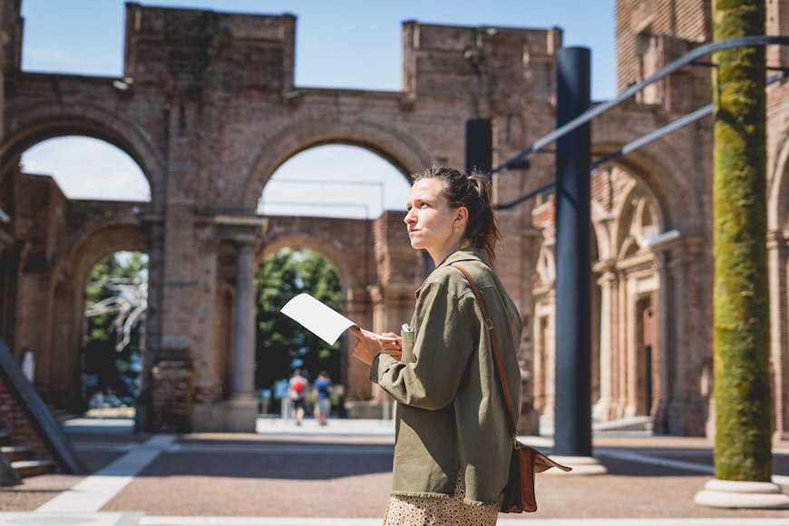 Белая брюнетка читает путеводитель во время посещения замка Риволи недалеко от Турина.  Девушка исследует город Пьемонт, Италия.