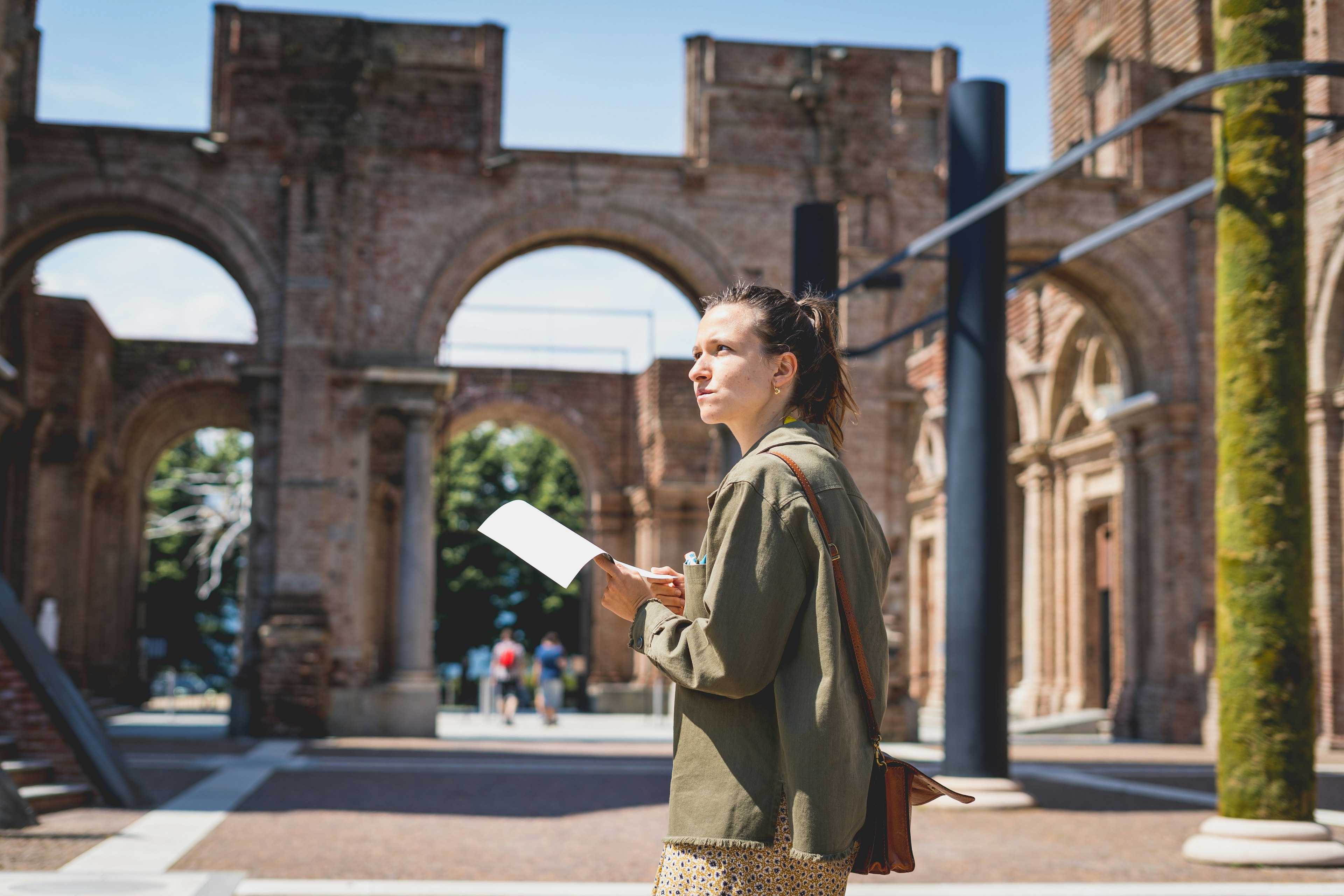 A brunette white woman reading a guidebook whilst visiting Rivoli castle near Turin. Girl explore Piemonte, Italy