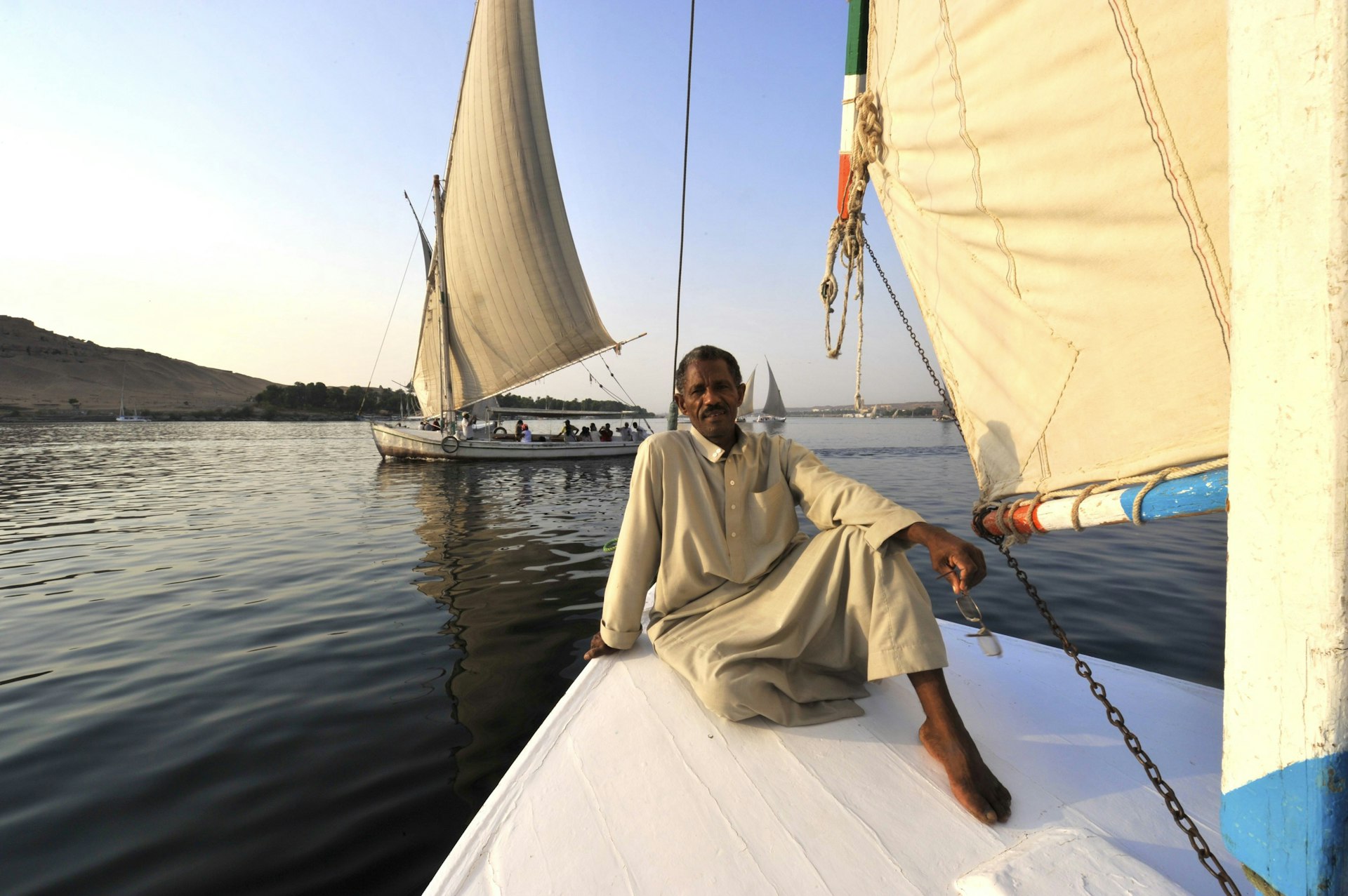 Boatman on the bow of a traditional Egyptian felucca sailing on the Nile River