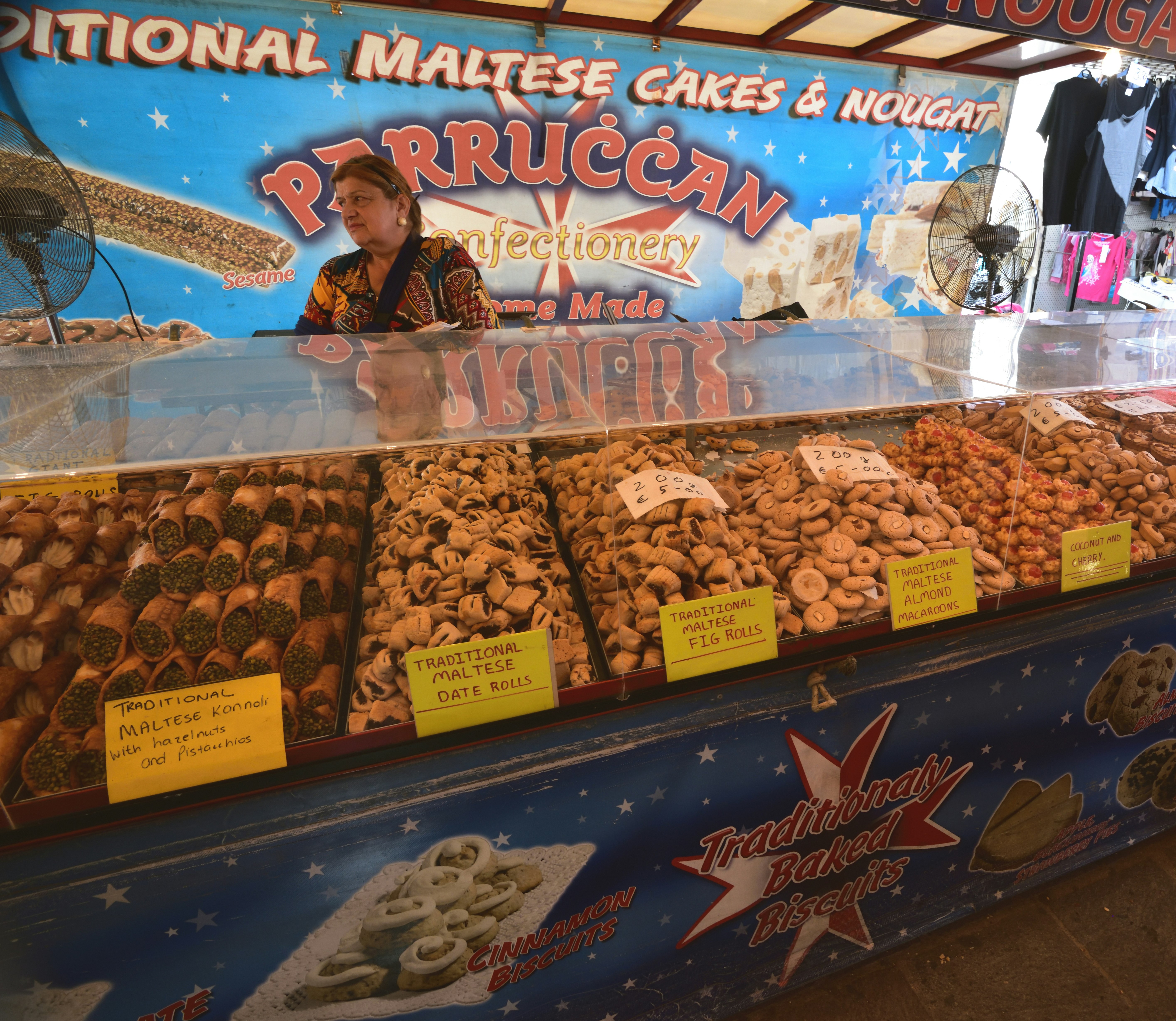 A vendor sells traditional sweets at stall in the market of Marsaxlokk, Malta, Europe