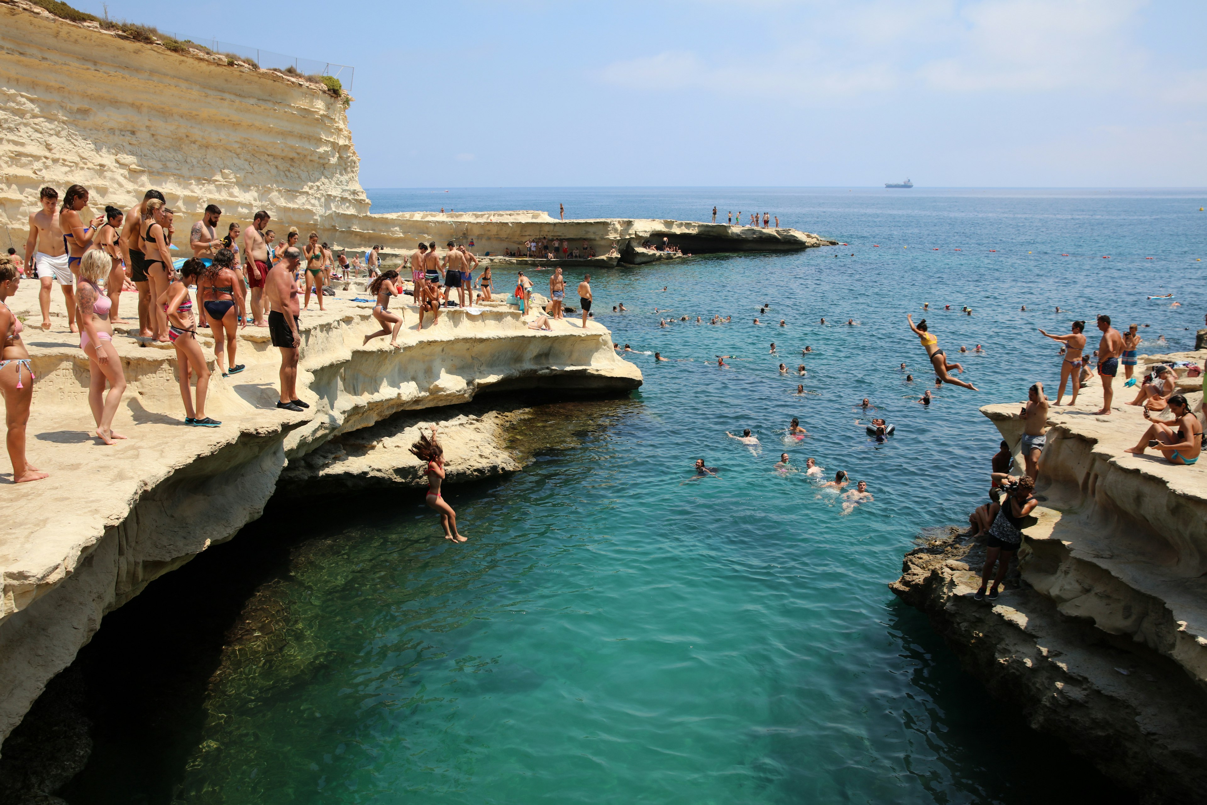 People jumping into the deep waters at St Peter's Pool near Marsaxlokk, Malta