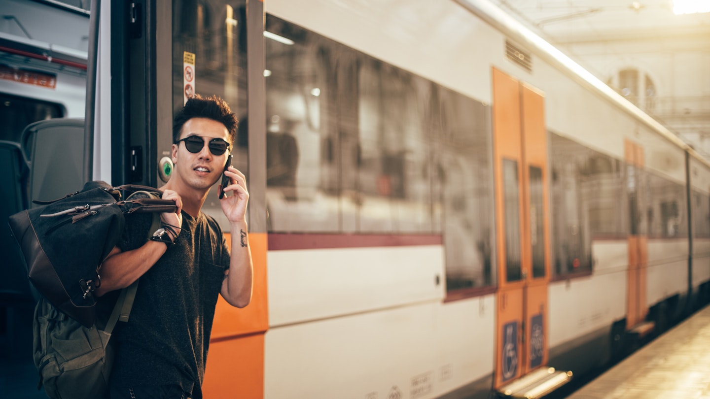 Chinese man leaving the train at train station and using phone