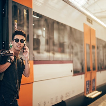 Chinese man leaving the train at train station and using phone