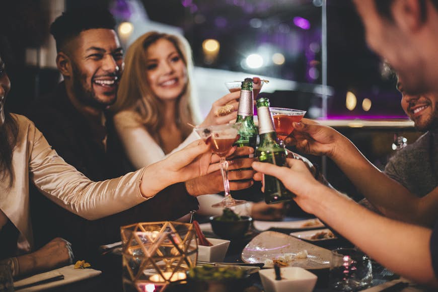 Grupp vänner som klirrar i glasögon medan de njuter av en kvällsmåltid på en restaurang på nyårsafton