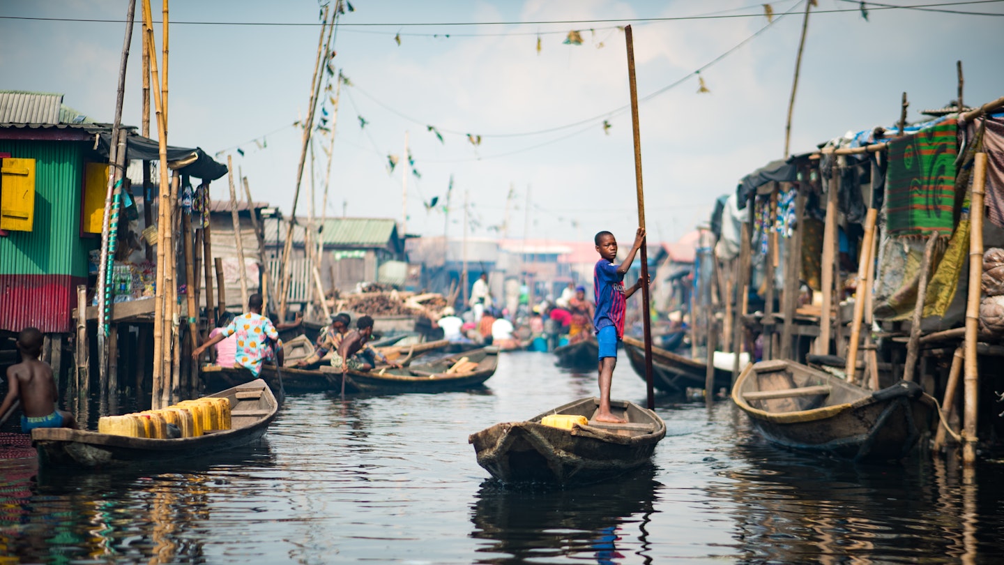 A young boy rowing a Canoe in the Makoko Stilts Village, Lagos/ Nigeria taken on the 18th of May, 2019; Shutterstock ID 1406396870; your: Brian Healy; gl: 65050; netsuite: Lonely Planet Online Editorial; full: Things to know before Lagos