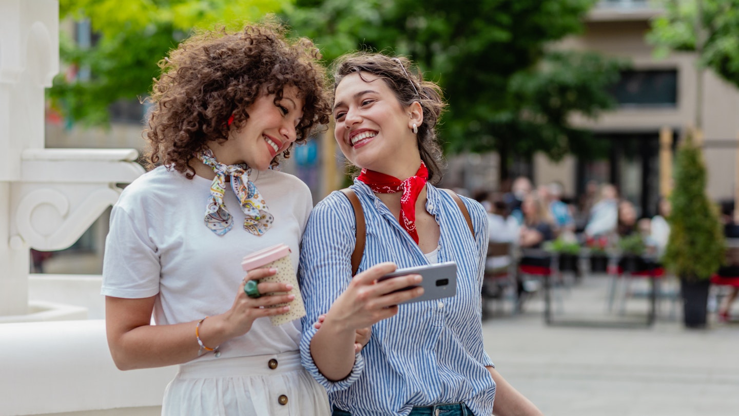 Photo of two female friends walking together and having fun together