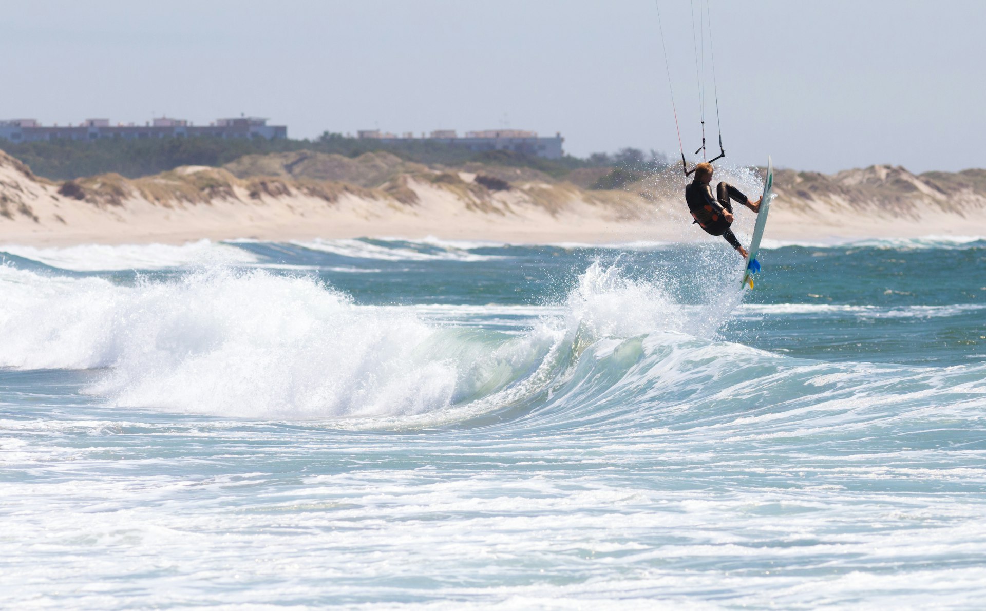 Athletic man kiteboarding on sea waves in Cabedelo Beach, Viana do Castelo, Portugal