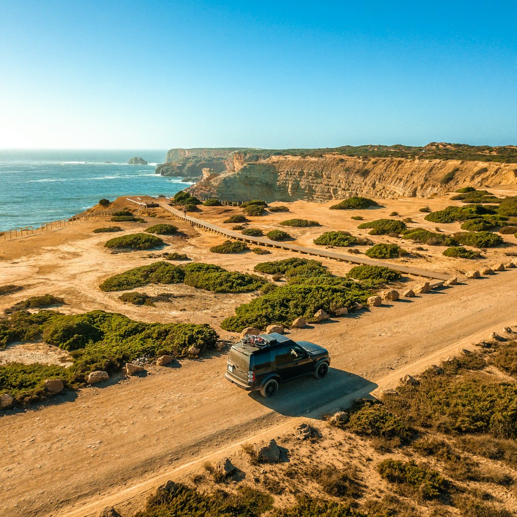 Algarve, Portugal - August 2020: Lifestyle photo of a black Land Rover Discovery 4 driving along scenic Portuguese coastline.; Shutterstock ID 1912082461; your: Brian Healy; gl: 65050; netsuite: Lonely Planet Online Editorial; full: Best road trips in Portugal