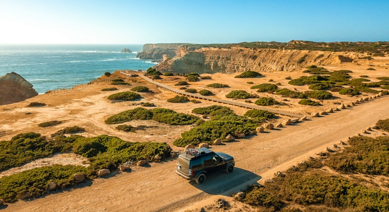 Algarve, Portugal - August 2020: Lifestyle photo of a black Land Rover Discovery 4 driving along scenic Portuguese coastline.; Shutterstock ID 1912082461; your: Brian Healy; gl: 65050; netsuite: Lonely Planet Online Editorial; full: Best road trips in Portugal