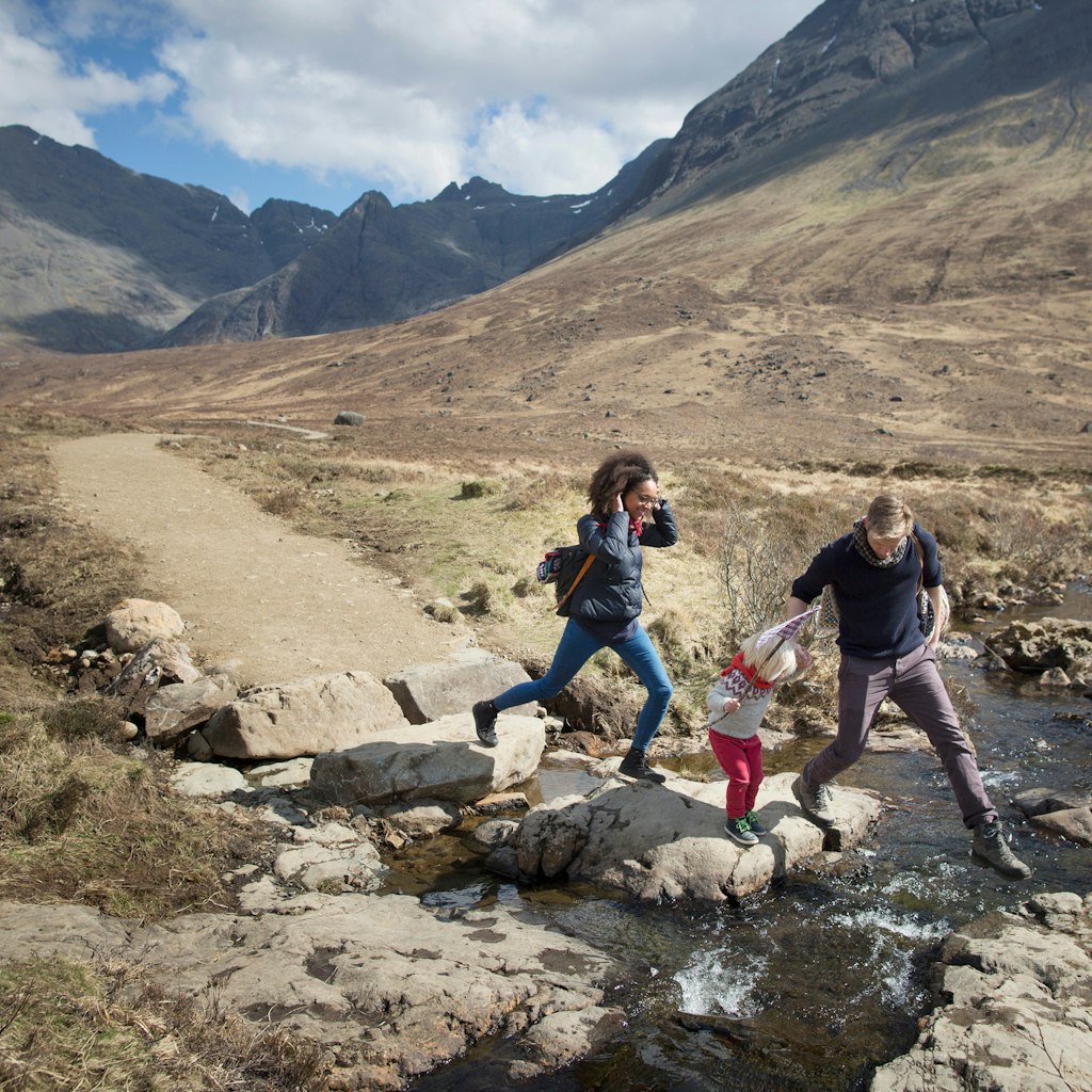Family crossing stream, Fairy Pools, Isle of Skye, Hebrides, Scotland