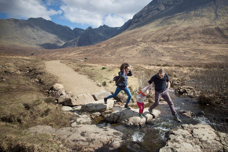 Family crossing a stream on the Isle of Skye, Scotland