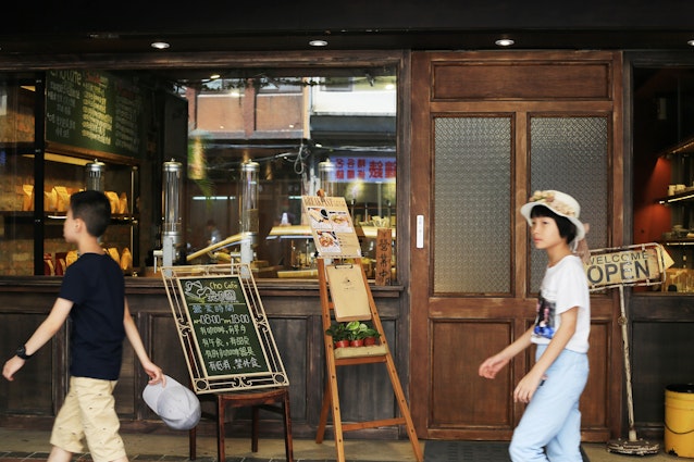 Two people walk past a small cafe in Taipei